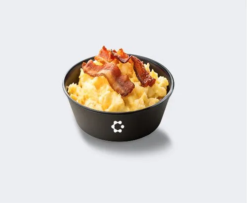 A black bowl with green soup topped with croutons and herbs, featuring a white Circus icon on the front.