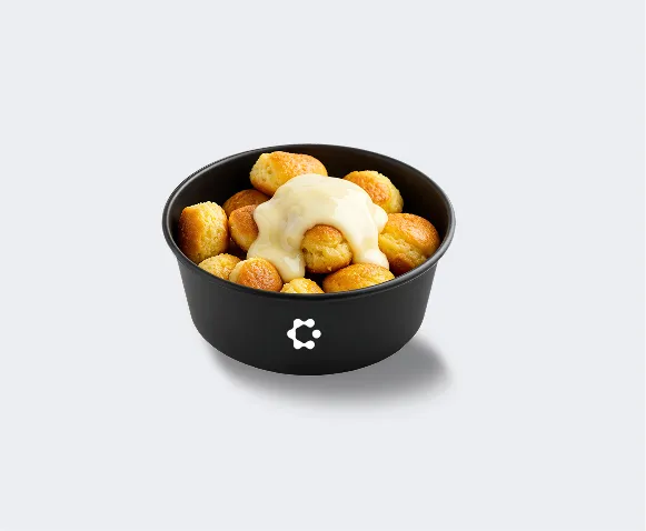 A black bowl with green soup topped with croutons and herbs, featuring a white Circus icon on the front.