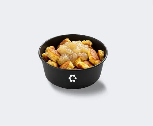 A black bowl with green soup topped with croutons and herbs, featuring a white Circus icon on the front.