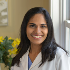 A woman in white lab coat smiling for the camera.