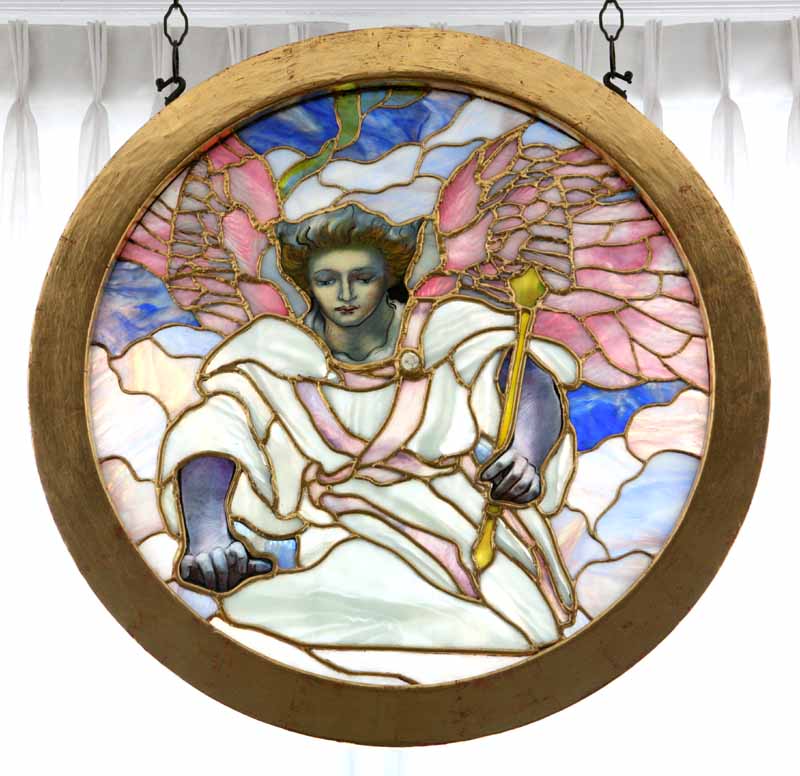 Round stained glass window depicting an angel with pink wings holding a gold scepter against clouds and sky.