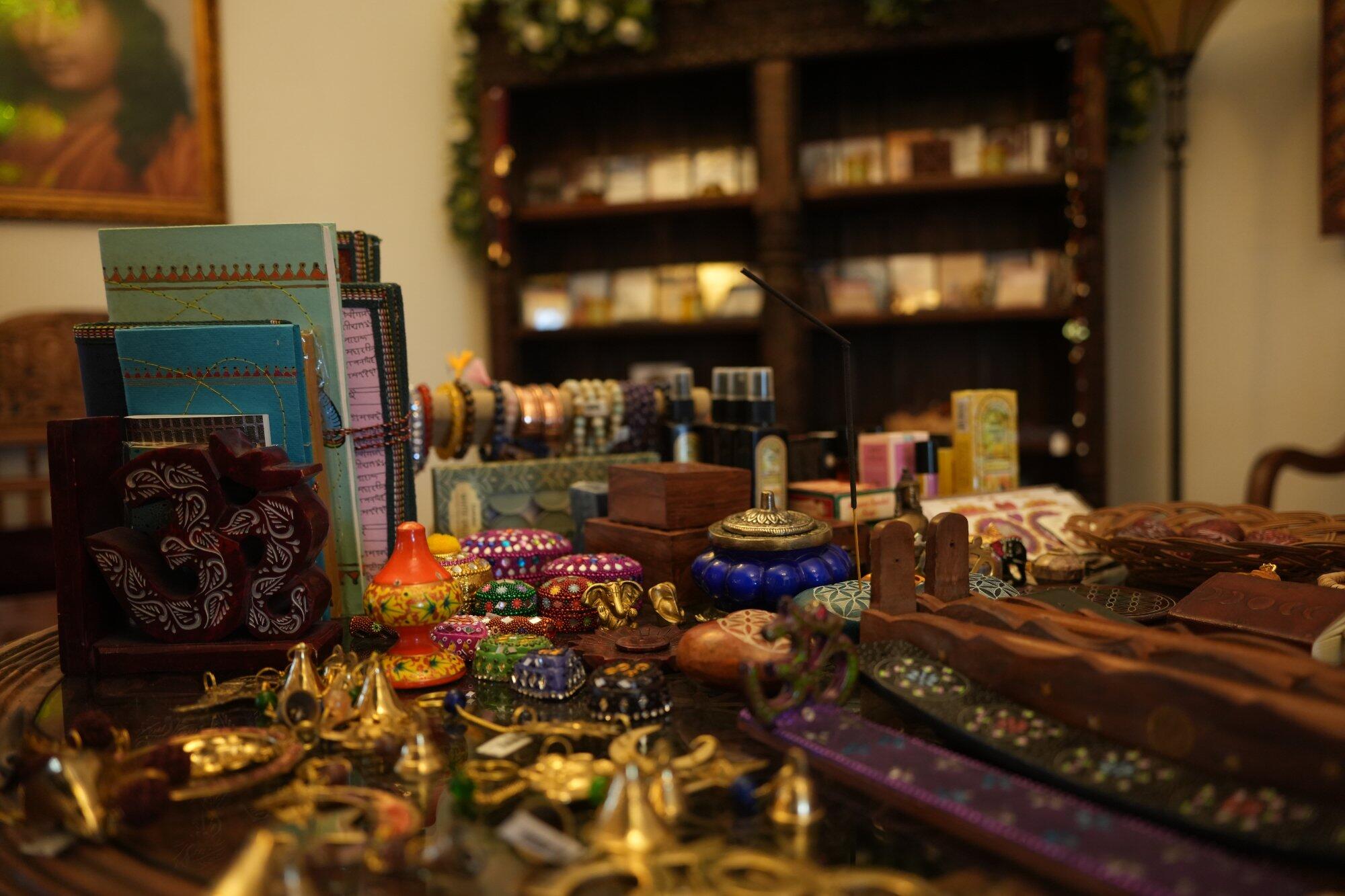 Table with assorted colorful jewelry, decorative boxes, incense holder, and handcrafted items in a cozy room.