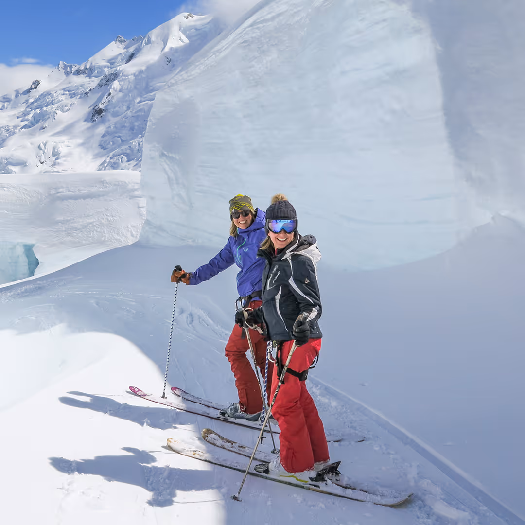 Tasman Glacier skiers navigating towering seracs amid dramatic alpine scenery.