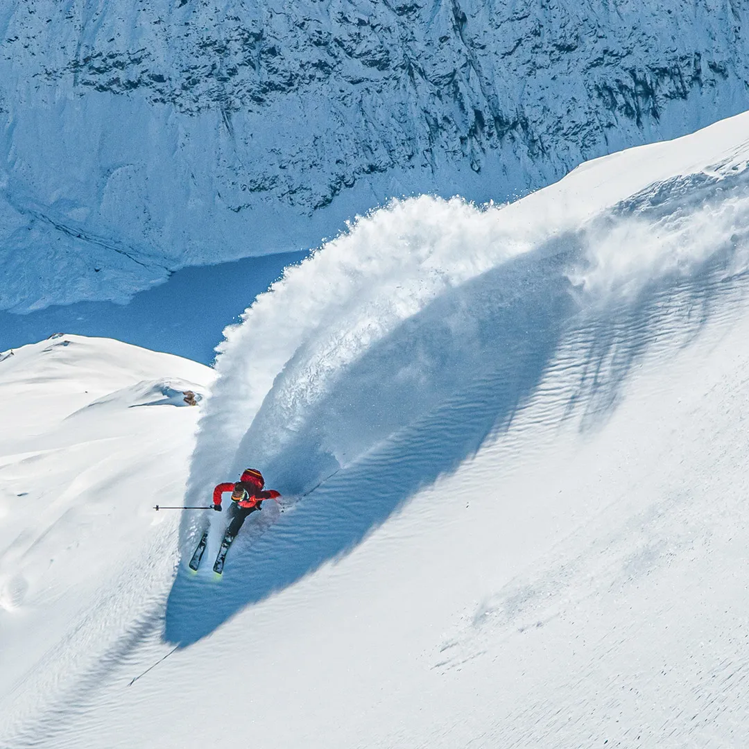 Mount Cook Heliski skiers carving through deep, fresh powder in alpine terrain.
