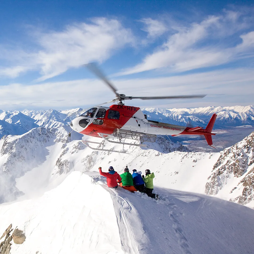 Methven Heliski helicopter dropping skiers onto a snowy mountain ridge for backcountry skiing.
