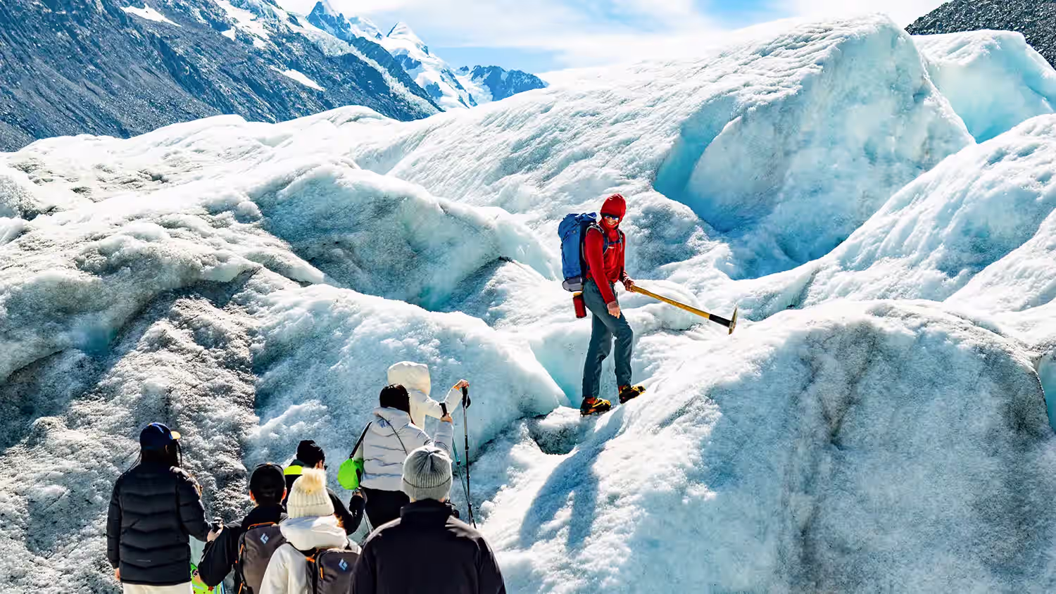 Group observe their helihike guide cutting steps on the glacier.