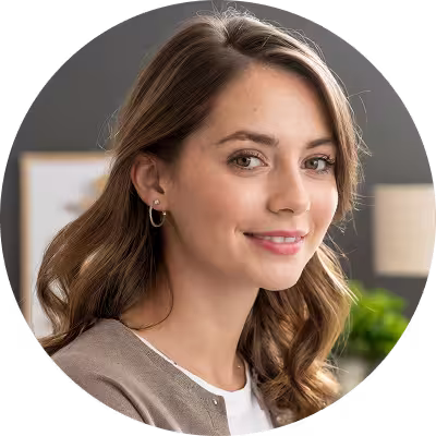 Circular portrait avatar of a smiling woman in a bright indoor setting.