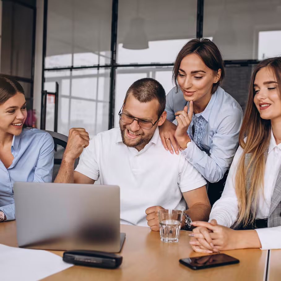 Coworkers gathered around a laptop, discussing ideas in a modern workspace.