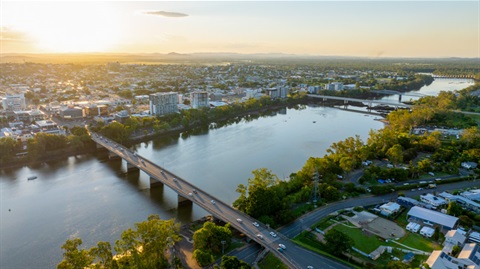Aerial view of Rockhampton showing a river, bridge, and surrounding urban area at sunset.