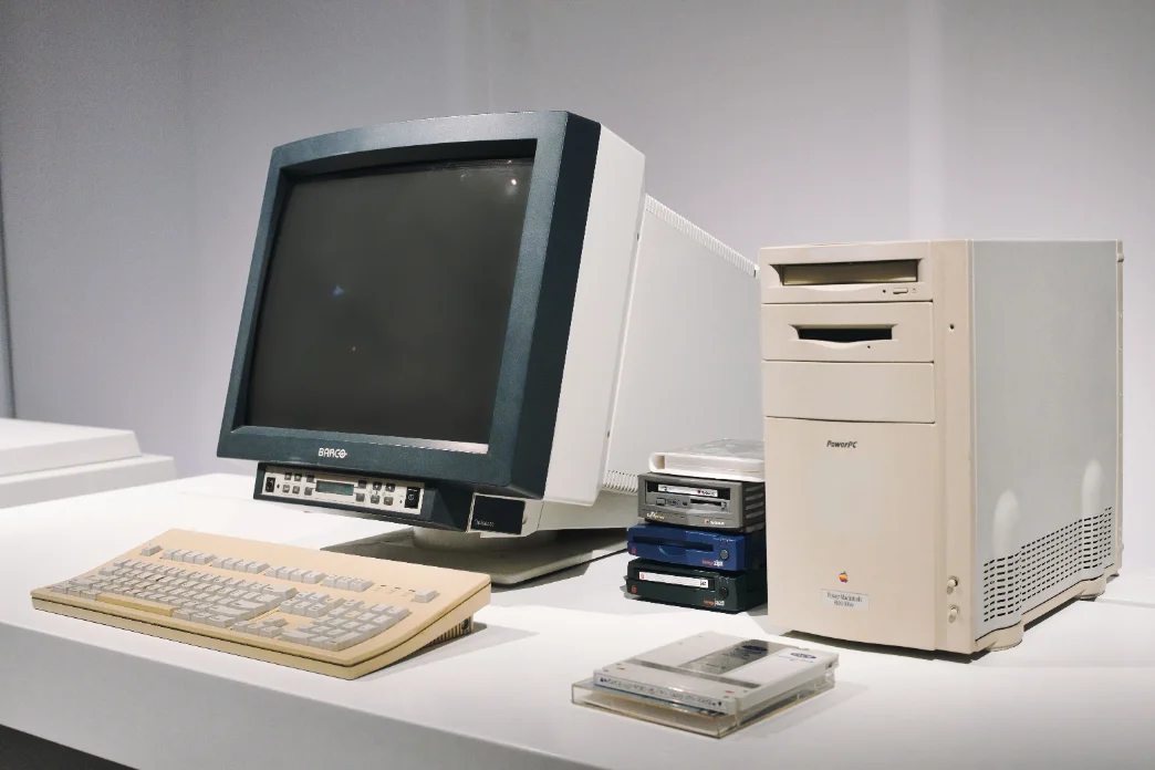 A team gathered around a beige desktop computer in a late-1990s dial-up era office