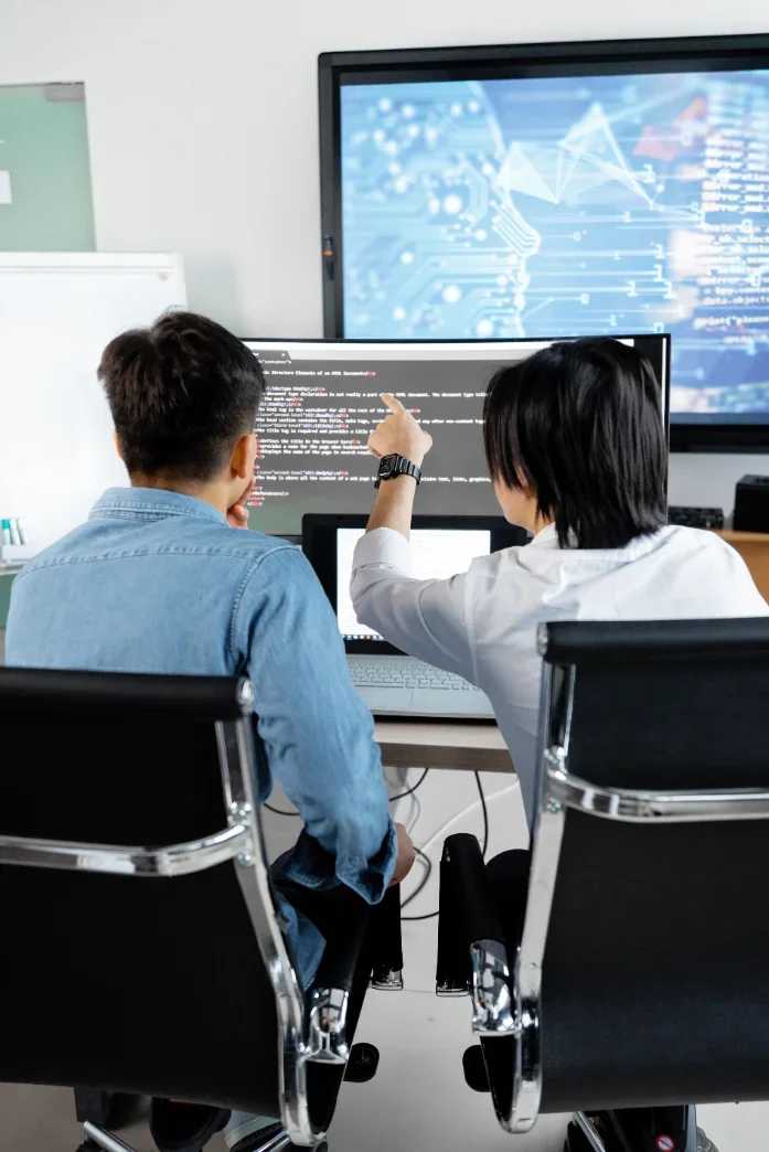 An engineer pairing with an AI coding assistant on a large bright screen in a modern office