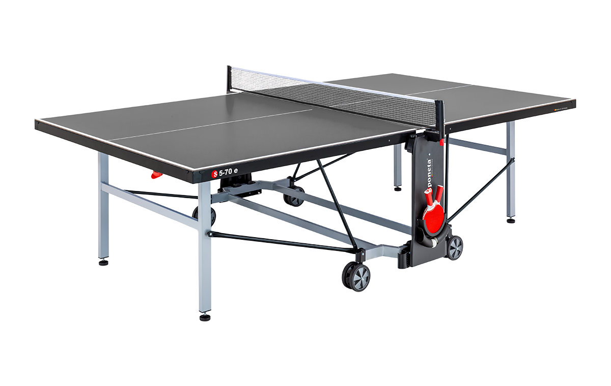 Szara składana stolik do tenisa stołowego z siatką, trzema czerwonymi rakietami i piłeczką zamocowanymi na stojaku.