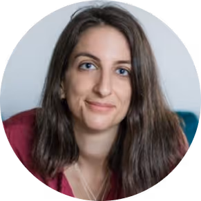 Portrait of a smiling woman with long brown hair wearing a maroon top.