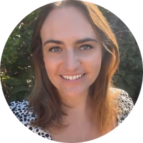 Smiling woman with shoulder-length brown hair outdoors in natural light.
