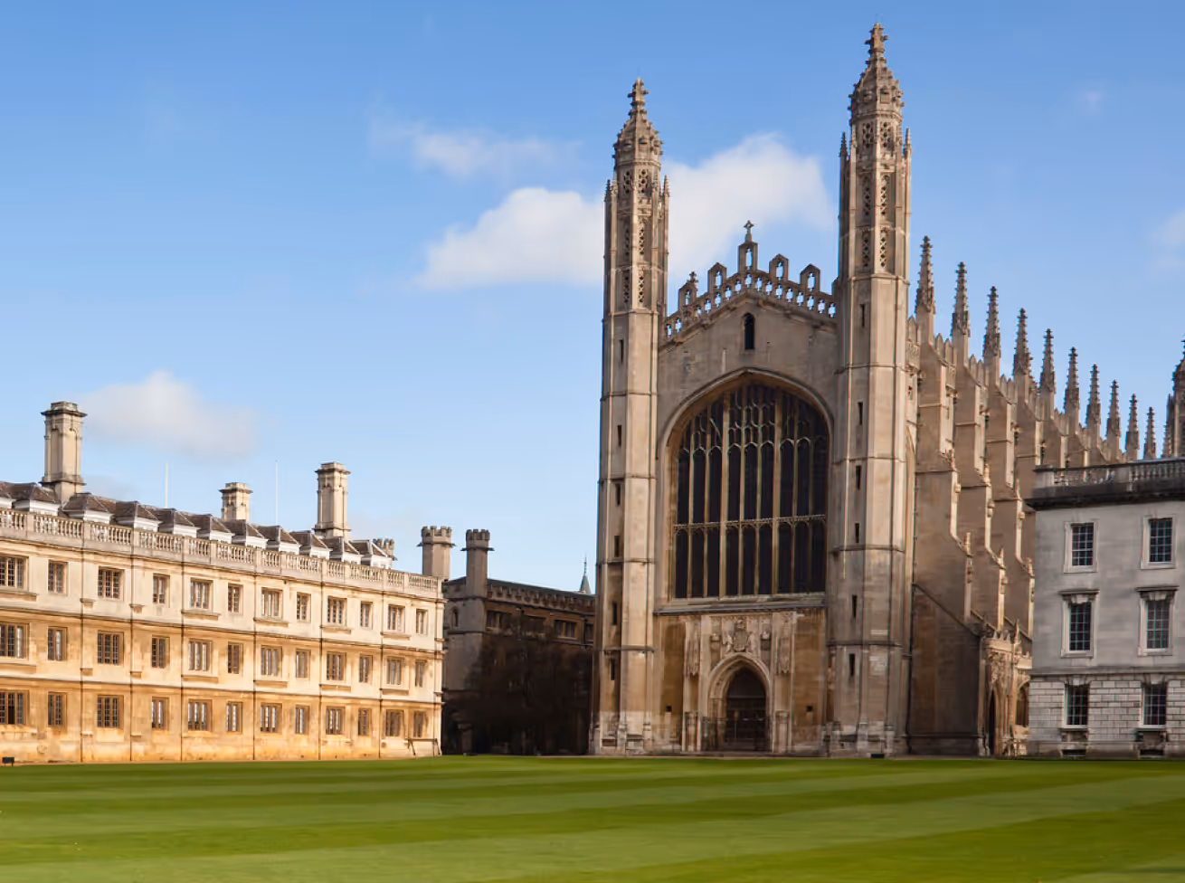King's College Chapel with gothic architecture and green lawn under blue sky.