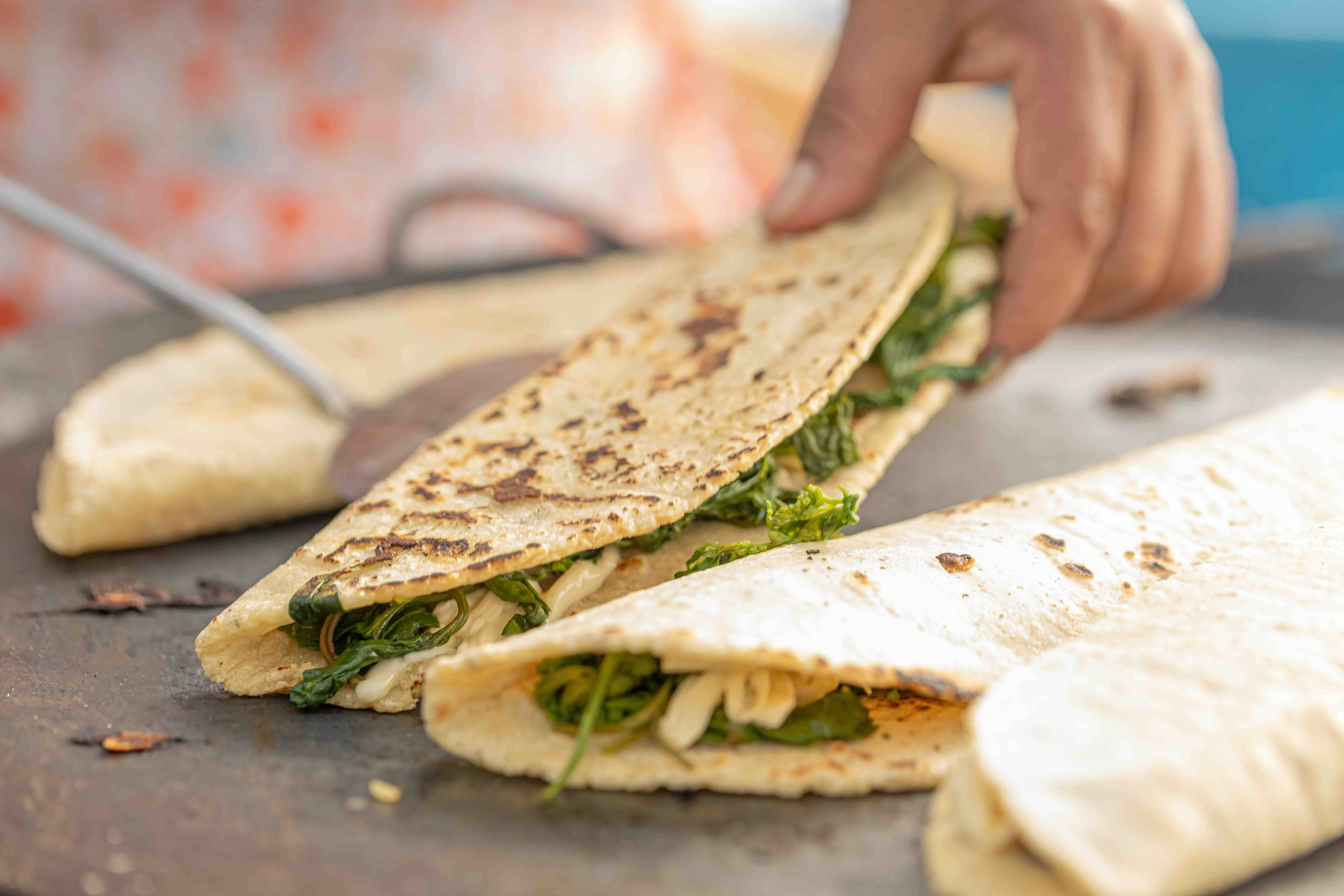 A fresh quesadilla with quelites inside of it being cooked on a large comal.