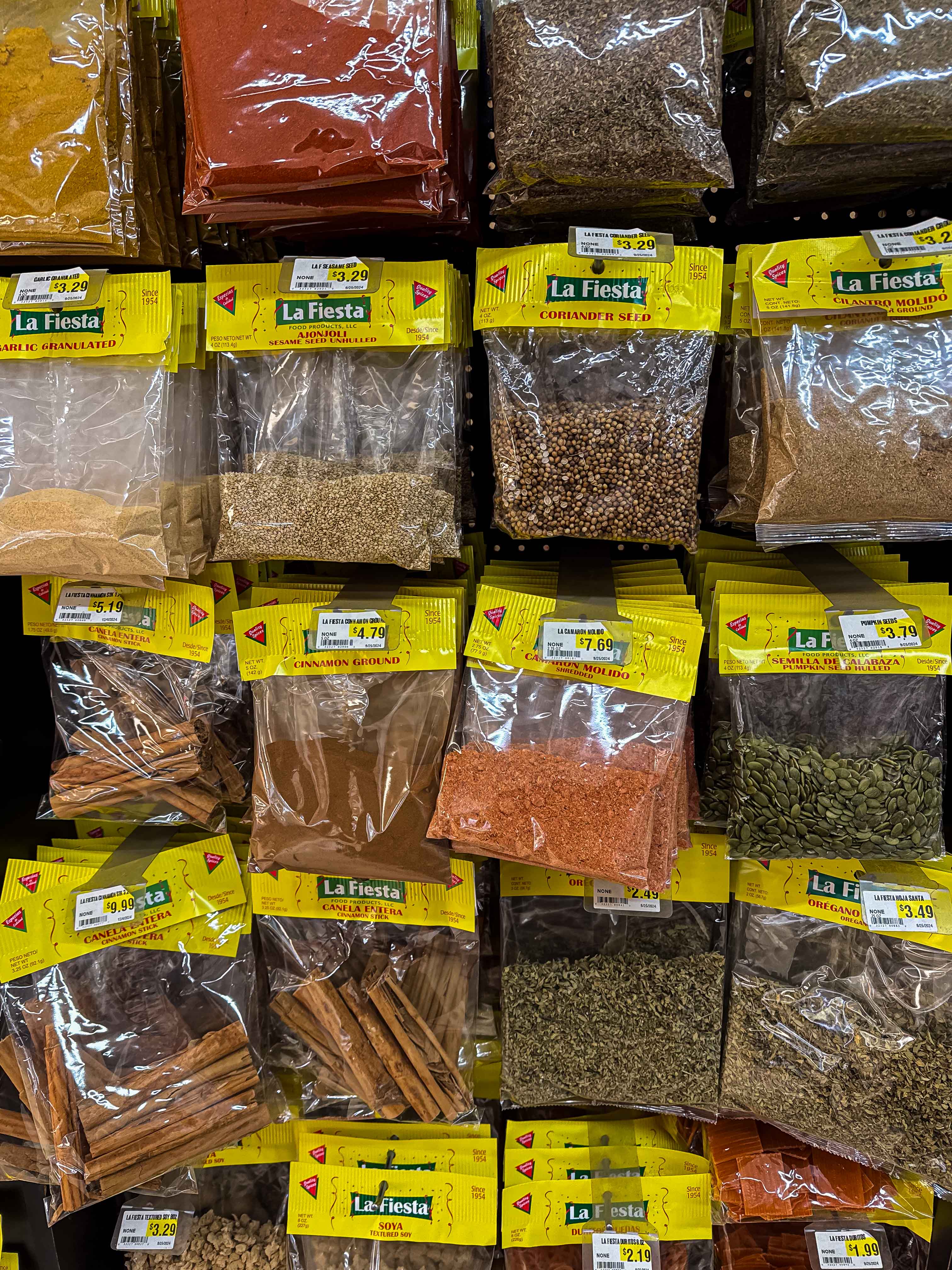 A variety of dried spices and seed hanging on a shelf in a Mexican market.