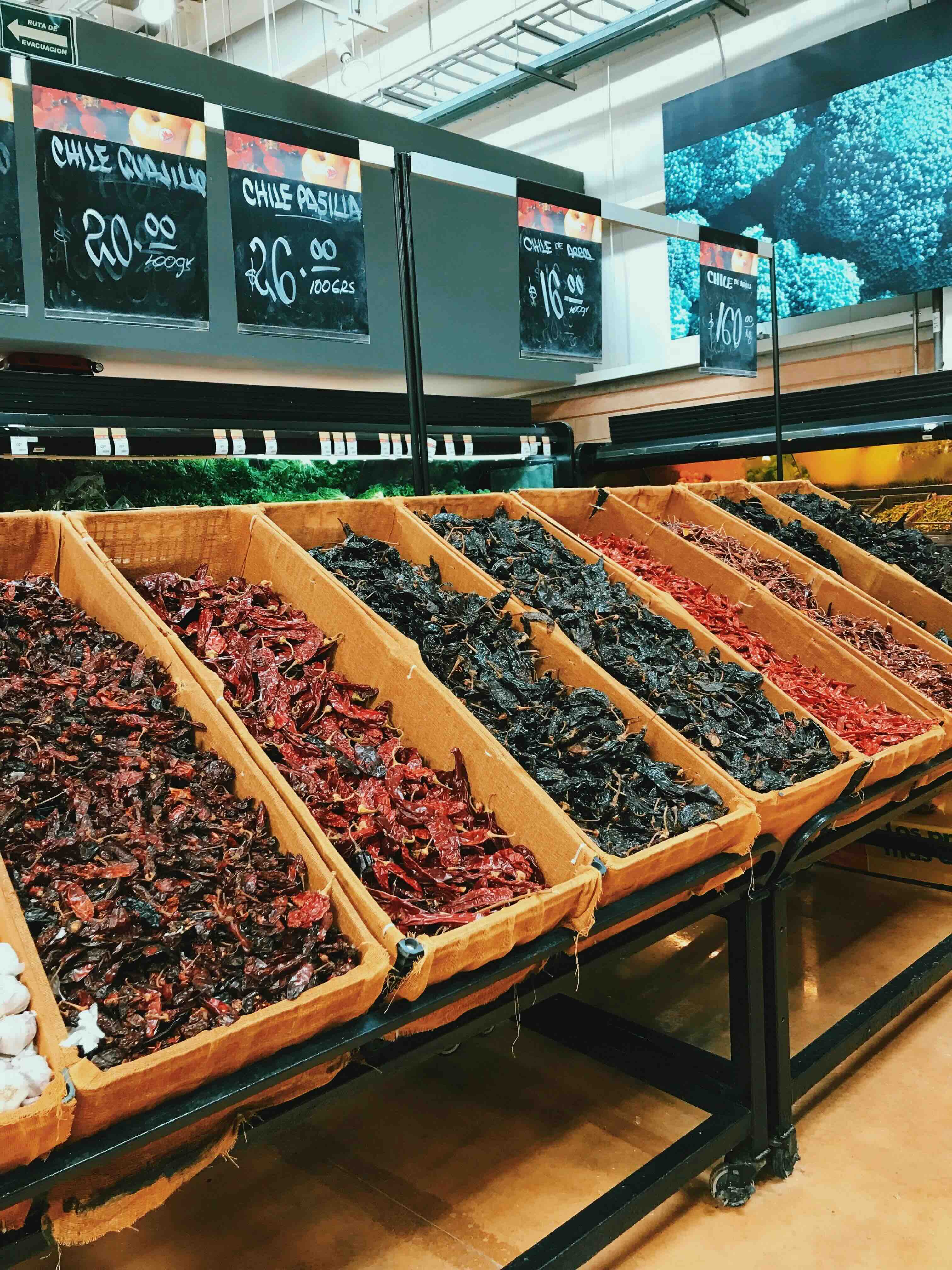Several bins of dried chilis in a grocery store.