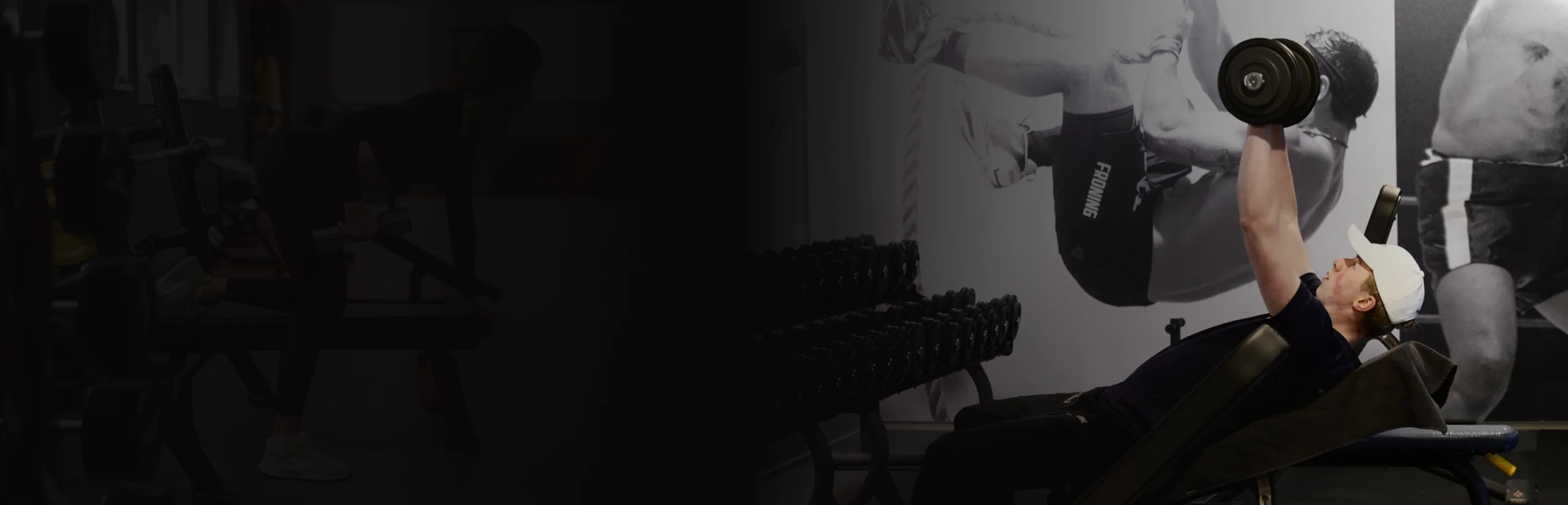 Man wearing a white cap performing incline dumbbell press in a gym with black and white fitness posters in the background.