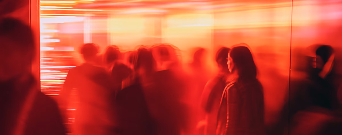 Blurred silhouettes of people moving in a red-lit indoor space with bright horizontal light streaks.