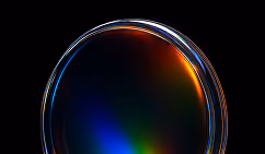 Close-up of a translucent circular lens with colorful light reflections on a black background.