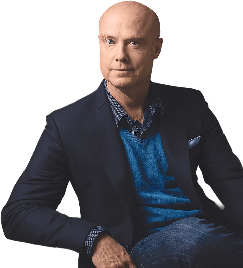 Ben Morley in a dark blazer, blue sweater, and checkered shirt sitting with a serious expression.