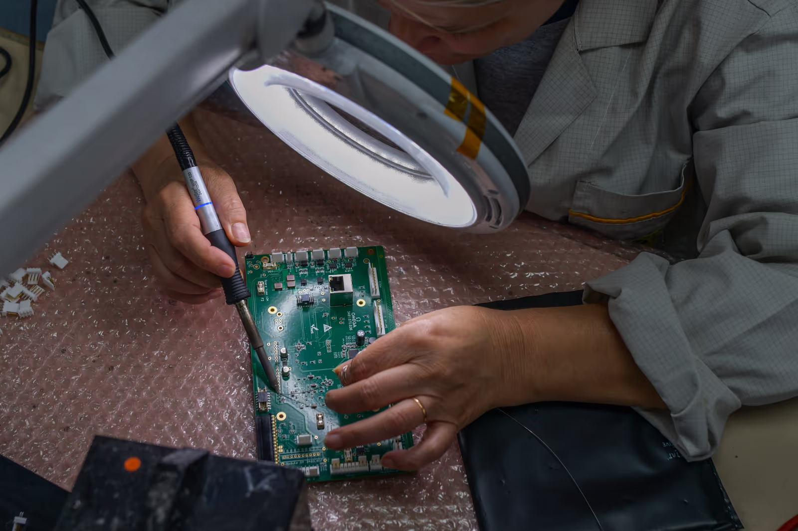 Une employée observe des soudures sous une loupe