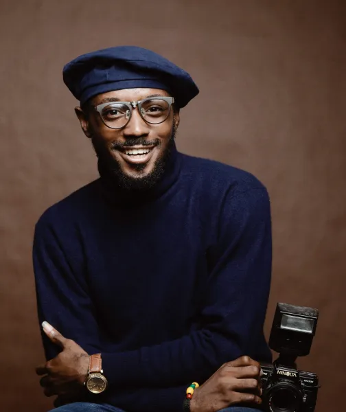 a man with a hat and glasses holding a camera - volunteer - best organization website webflow CMS template