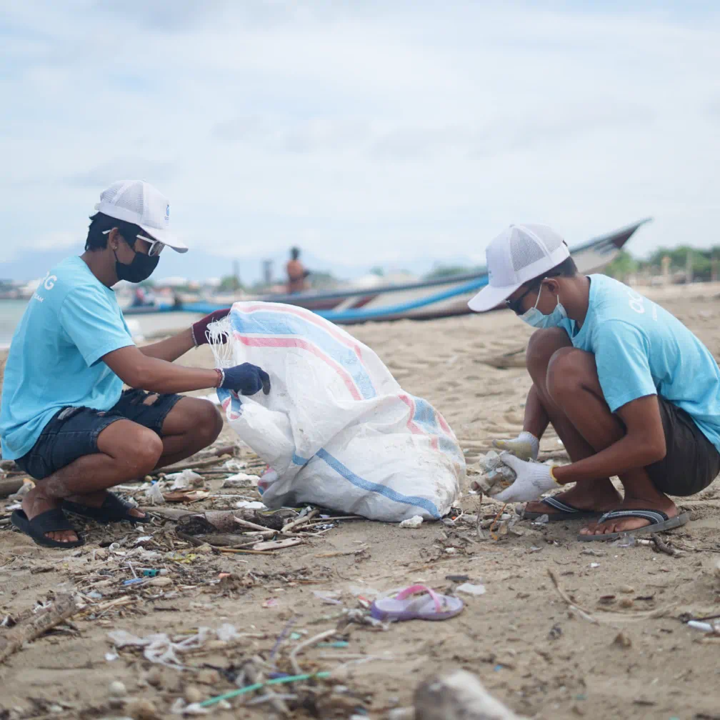 a couple of men standing on top of a sandy beach - volunteer - best organization website webflow CMS template