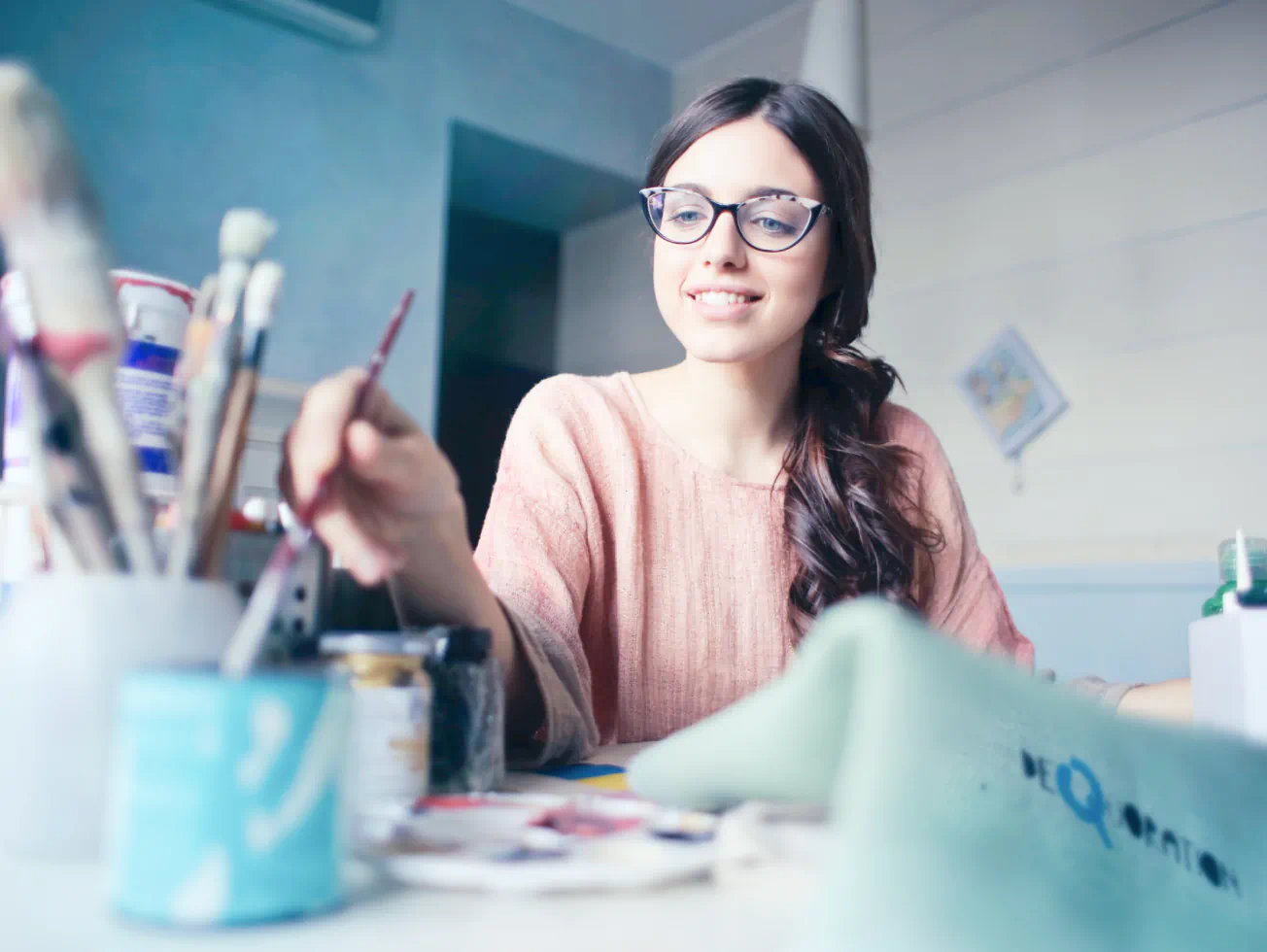a woman sitting at a table with paint and brushes - Volunteer - Best Organization Website Webflow CMS Template