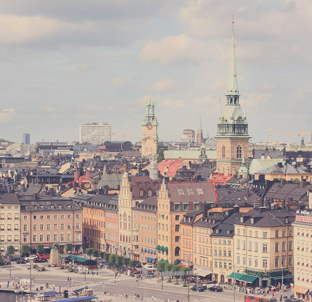 Scenic view of historic buildings and church towers in a European city square on a partly cloudy day.