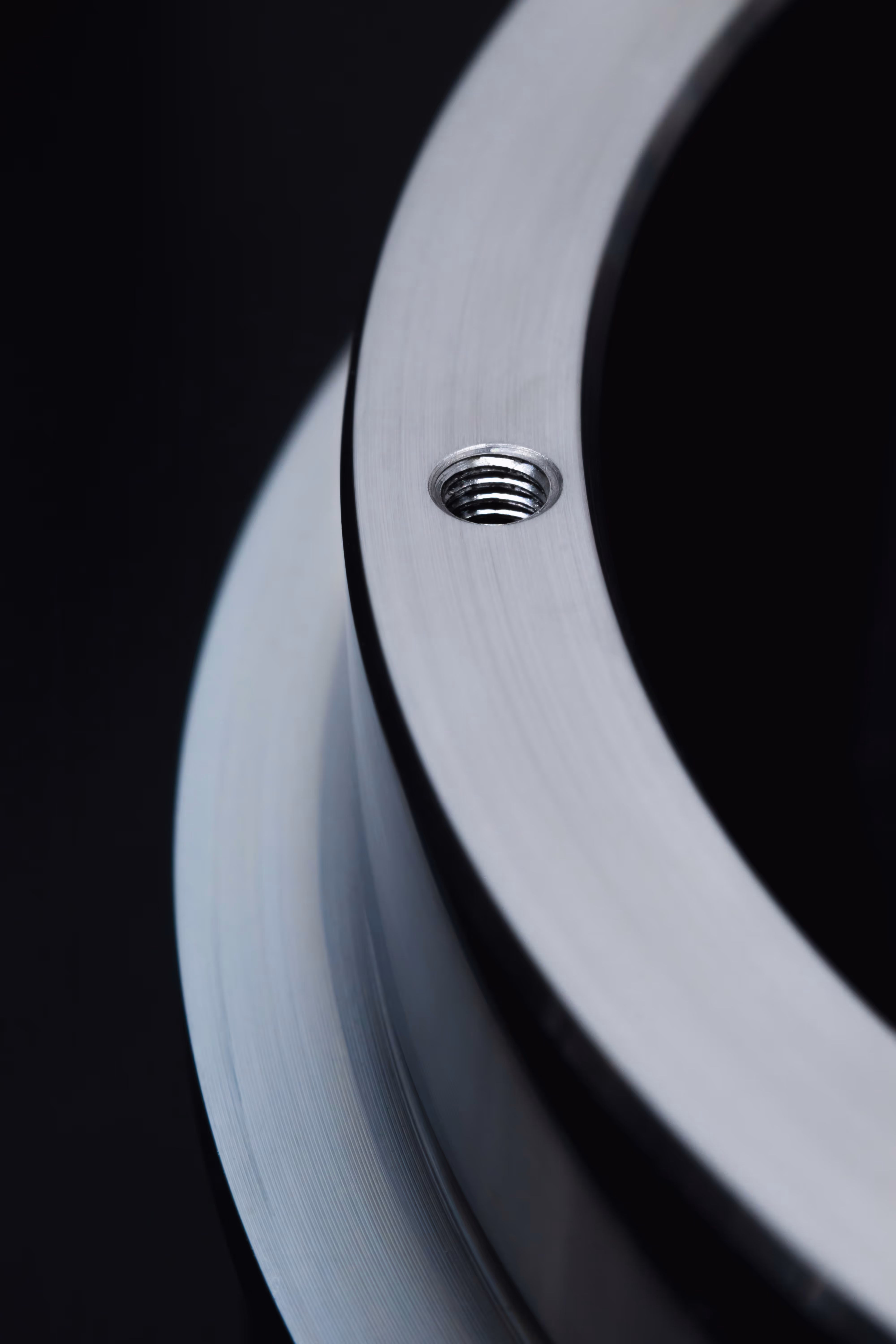 Close-up of a silver metal flange with a threaded hole on a black background.