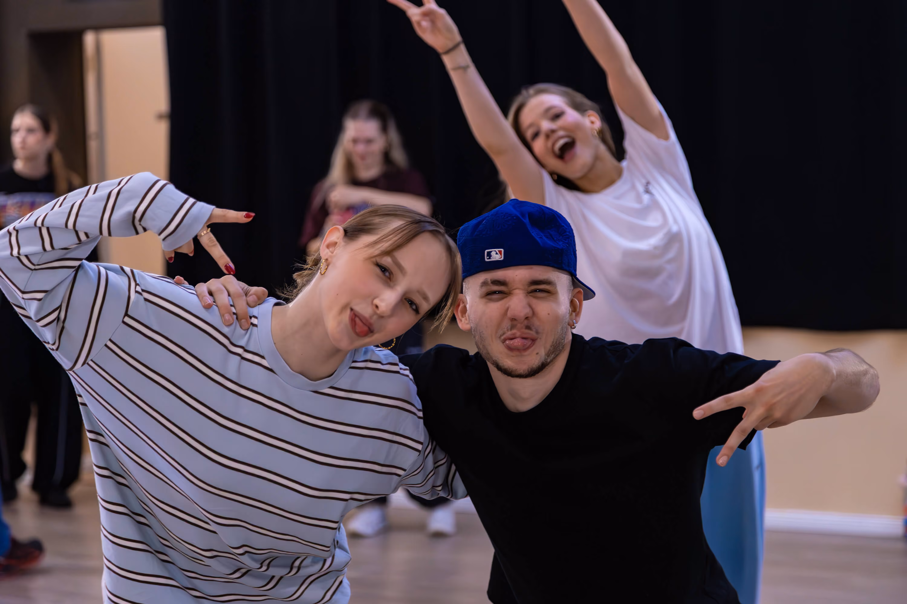 Zwei Tänzer posieren in der Tanzschule The Base Erfurt, während im Hintergrund eine Tänzerin die Arme hebt.
