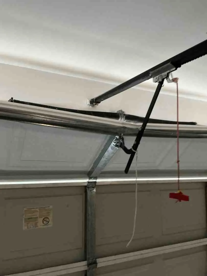 Infographic showing how torsion springs wind on a horizontal bar above the door and extension springs stretch along the side tracks, with labeled components including spring coils, cable drums, torsion bar, pulleys, and safety cables, illustrating how each type lifts and counterbalances the garage door weight - garage spring repair