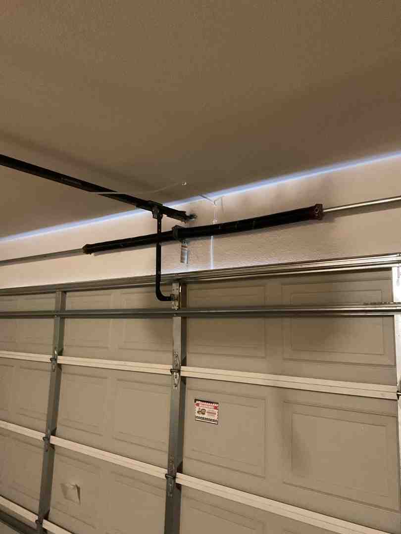 Infographic showing the anatomy of a residential garage door system including torsion springs, cables, rollers, tracks, sensors, and opener unit, with labels indicating common failure points and recommended inspection frequency - broken garage door repair north las vegas nv