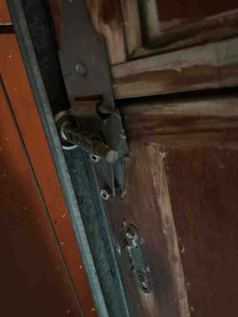 A professional technician carefully lubricating a garage door hinge with a spray lubricant, ensuring smooth operation and reducing wear and tear - garage door maintenance in lakeway tx