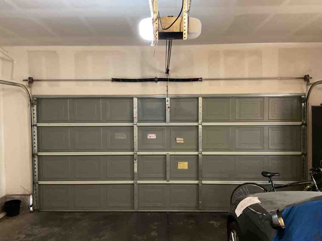 Homeowner in a garage manually lifting a sectional garage door from the center handle - power outage and your garage door