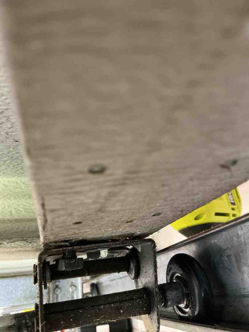technician lubricating garage door rollers and hinges with specialized lubricant - is a garage door maintenance plan worth it