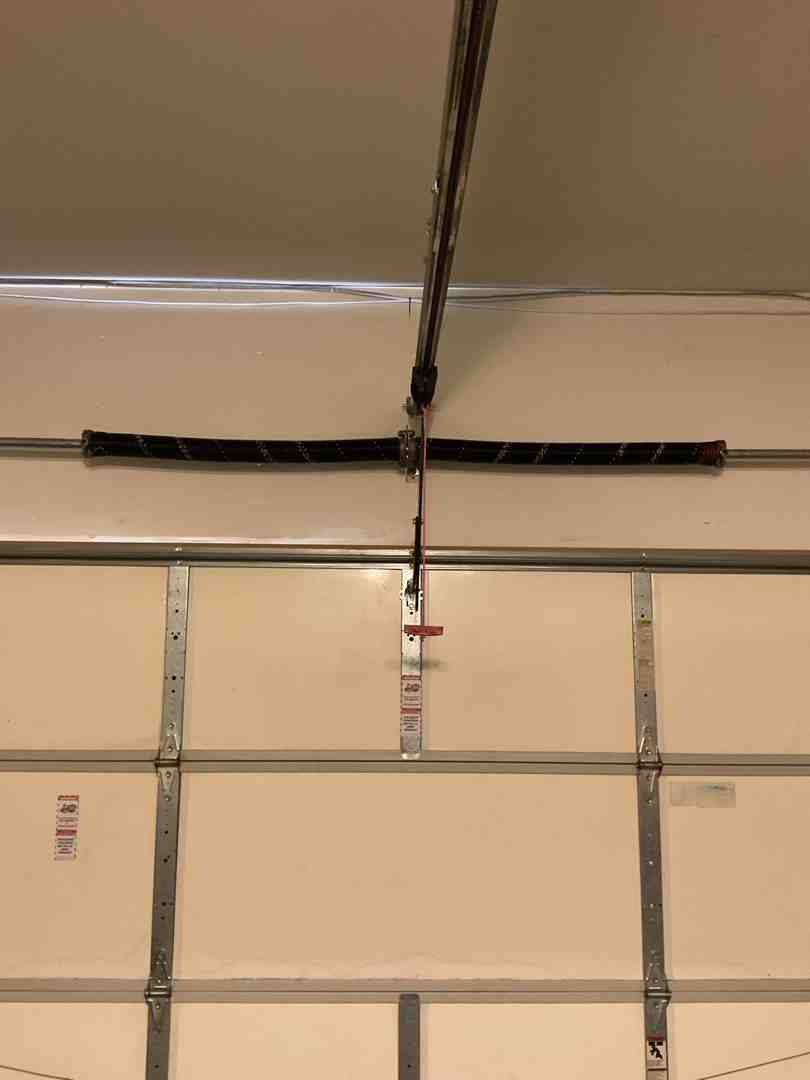 Torsion spring mounted on a metal shaft above a garage door