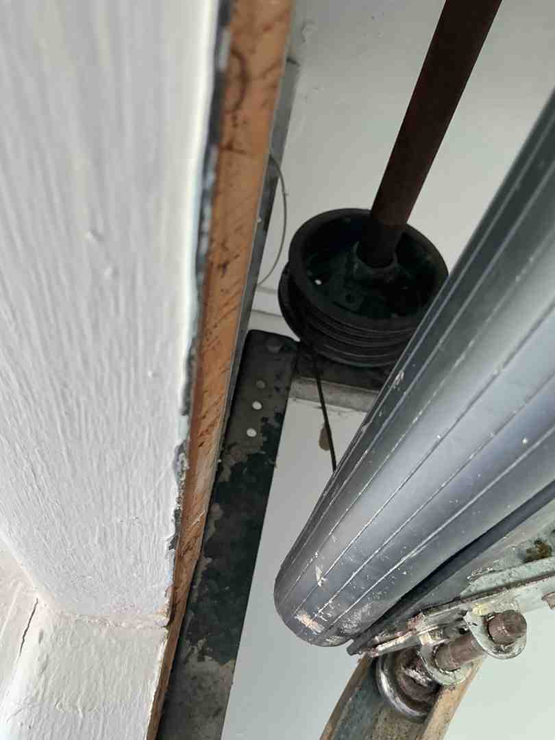 technician inspecting garage door springs rollers and tracks inside a residential garage