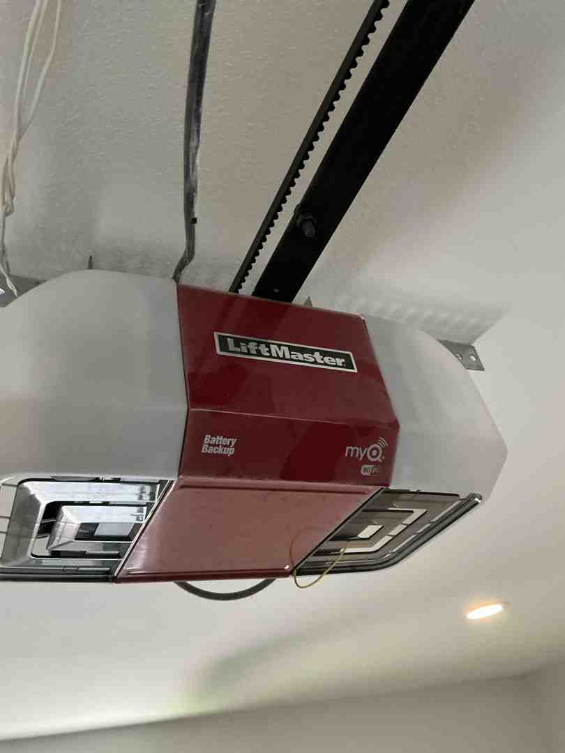 garage door opener components mounted inside garage with rail motor battery backup and safety sensors