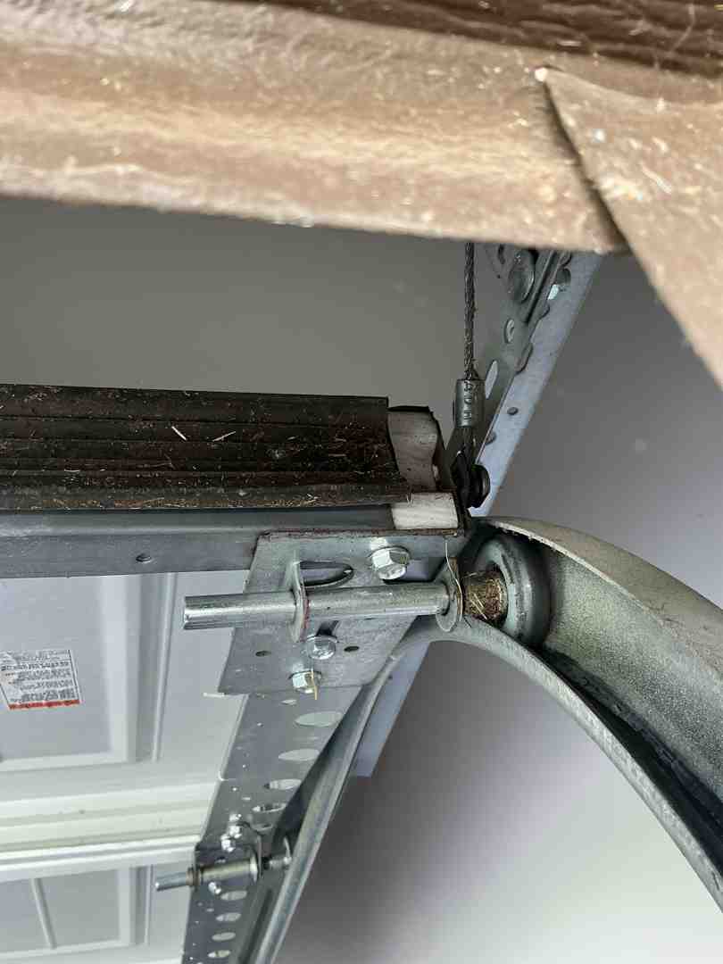 garage door tracks and steel rollers showing signs of friction and wear