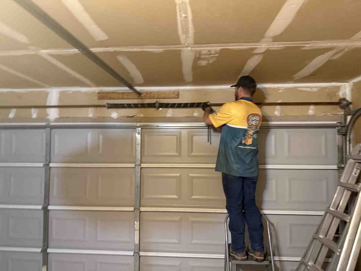 garage door technician repairing high-tension springs inside the garage garage door technician repairing high-tension springs inside the garage