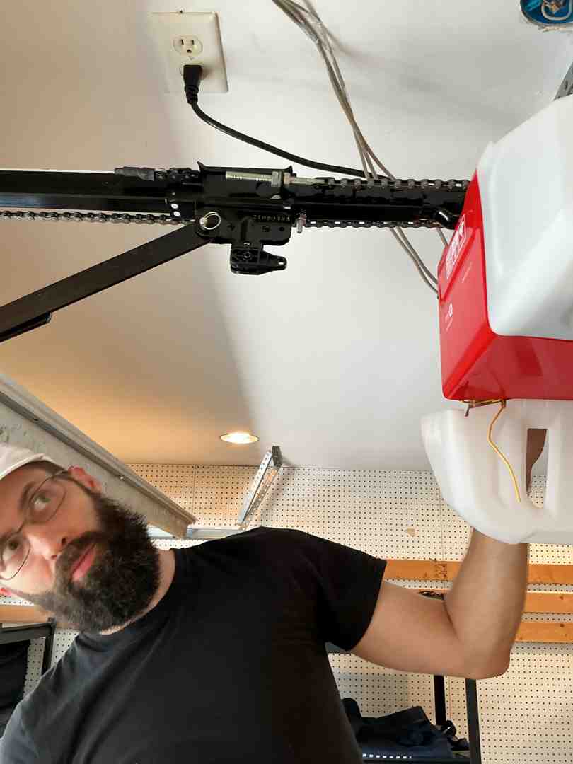 homeowner inspecting plugged-in garage door opener motor unit during power outage homeowner inspecting plugged-in garage door opener motor unit during power outage