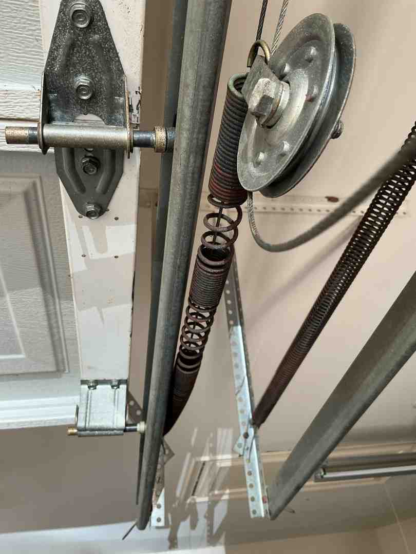Worn out garage door rollers and heavily rusted torsion springs showing severe mechanical fatigue Worn out garage door rollers and heavily rusted torsion springs showing severe mechanical fatigue