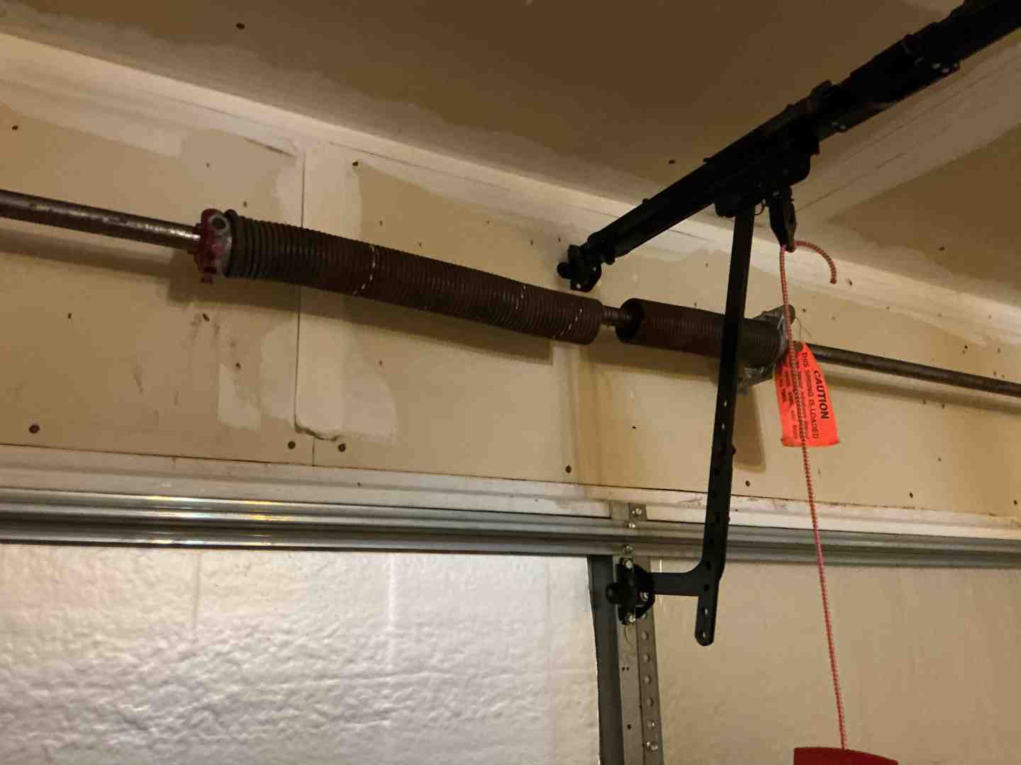 rusted garage door torsion spring mounted above a closed garage door inside a garage rusted garage door torsion spring mounted above a closed garage door inside a garage