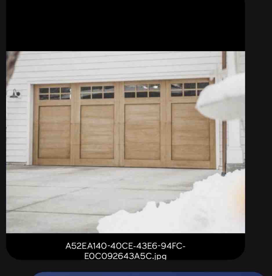 A beautiful faux-wood composite garage door installed on a modern farmhouse A beautiful faux-wood composite garage door installed on a modern farmhouse