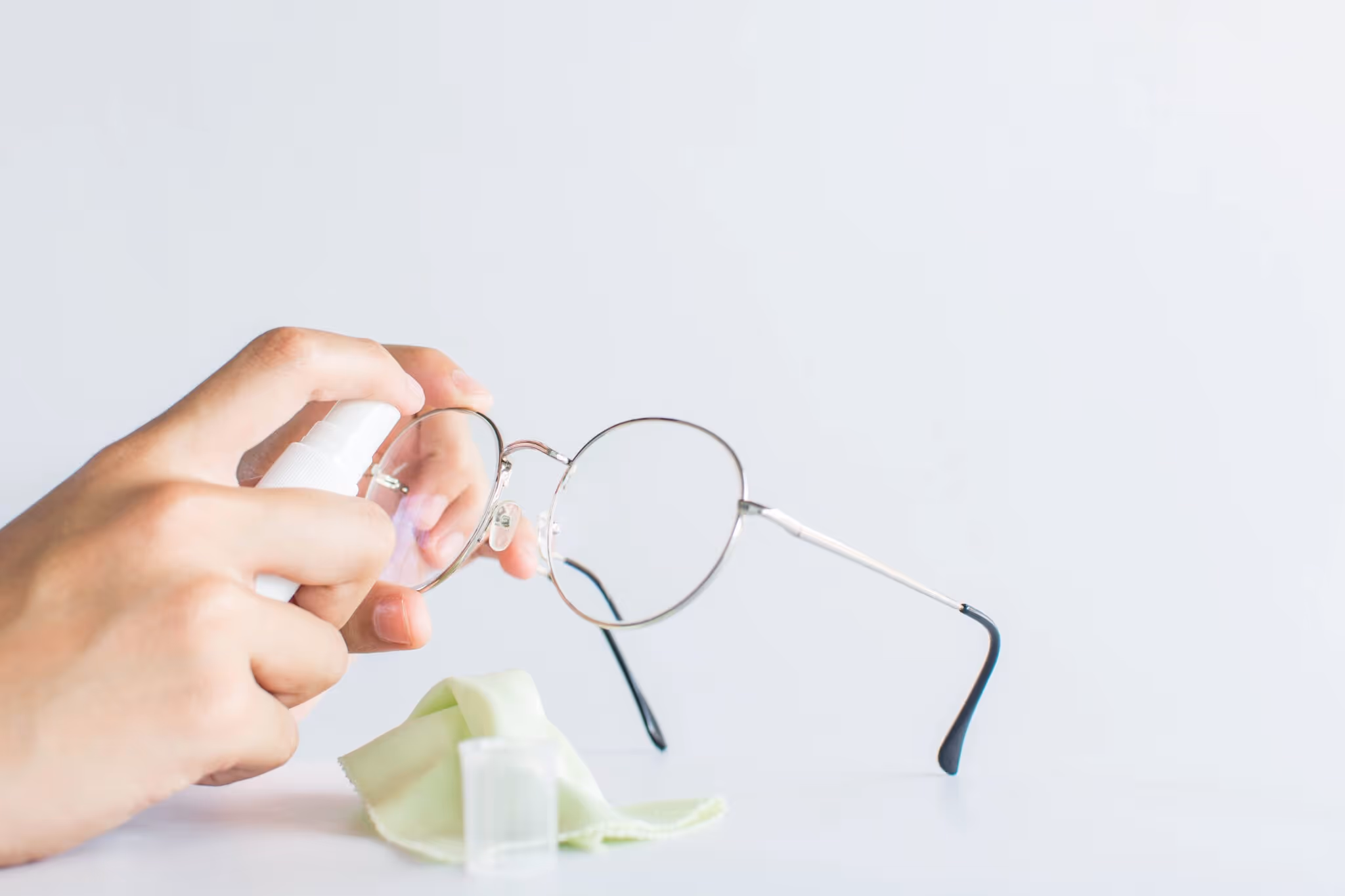 Eine Brille wird mit Spray und Brillenputztuch gereinigt.