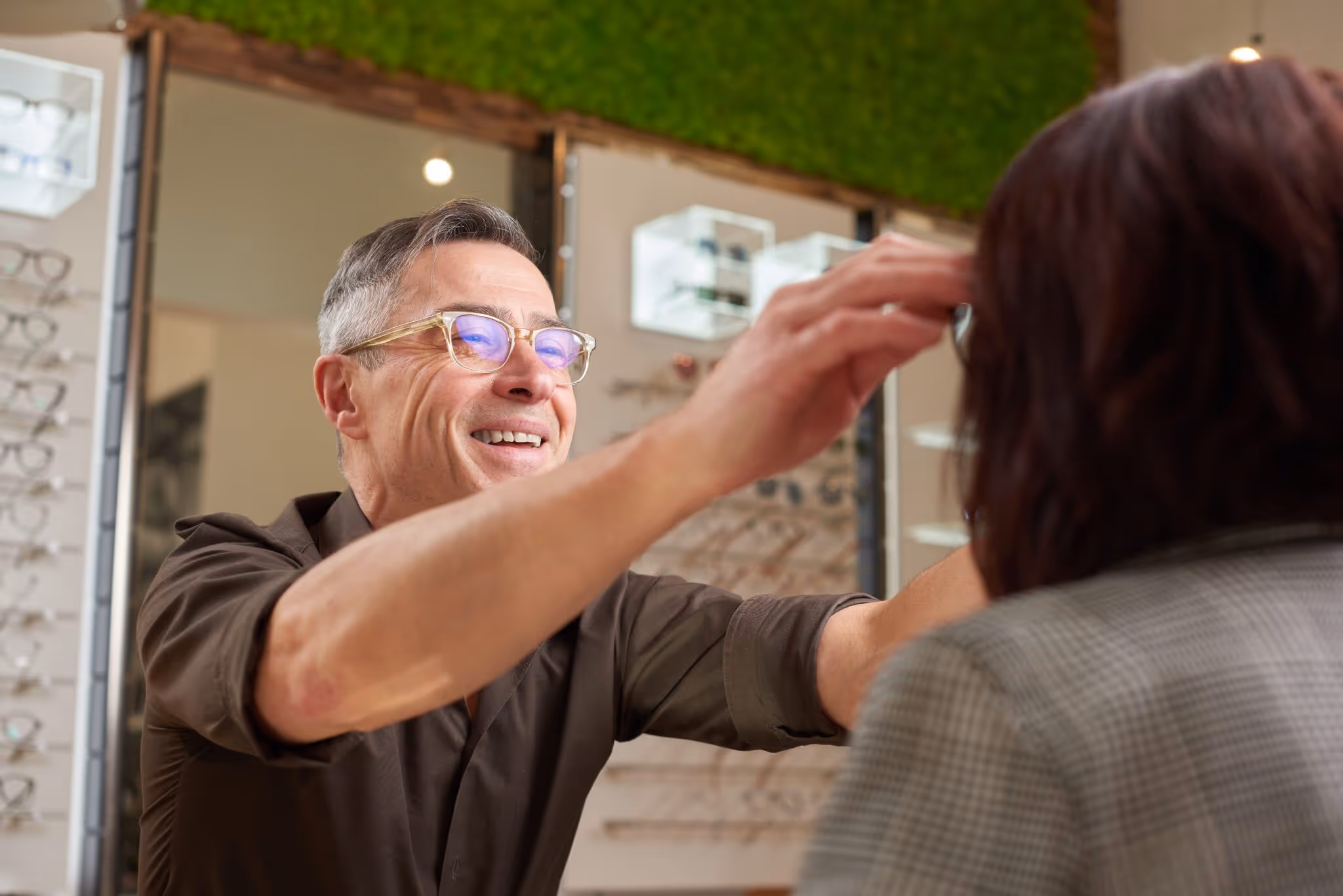 Reinhold Walter prüft die Passung einer handgefertigten Brille bei einer Kundin.
