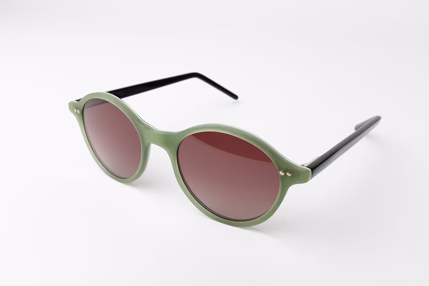 Runde Sonnenbrille mit grünem Rahmen und schwarzen Bügeln auf weißem Hintergrund.